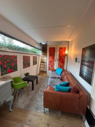 a living room with a brown leather couch and blue pillows at Huisje Vivaldi in Den Bosch