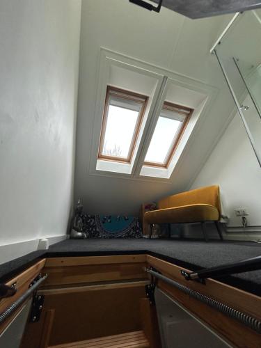 an attic room with a bench and two windows at Huisje Vivaldi in Den Bosch