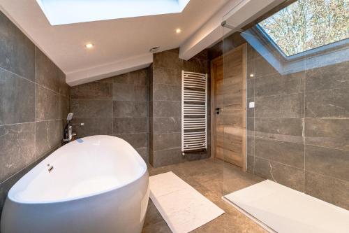 a bathroom with a large white tub and a skylight at Charmant chalet, spacieux, proche du lac, vue sur la montagne in Gérardmer