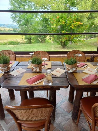 a wooden table with chairs and a large window at Agriturismo Il Mio Casale in Monte Colombo