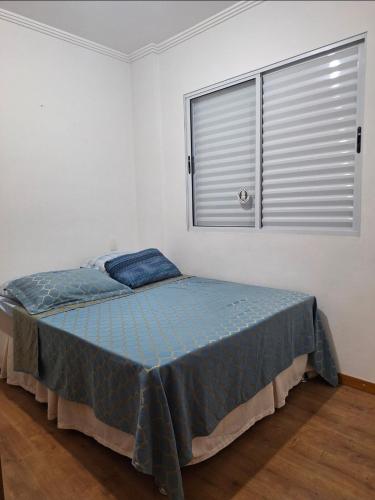 a bed in a white room with a window at Refúgio das montanhas - Centro in Poços de Caldas