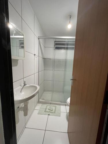 a white bathroom with a shower and a sink at Apartamento confortável para sua estadia in Teresina