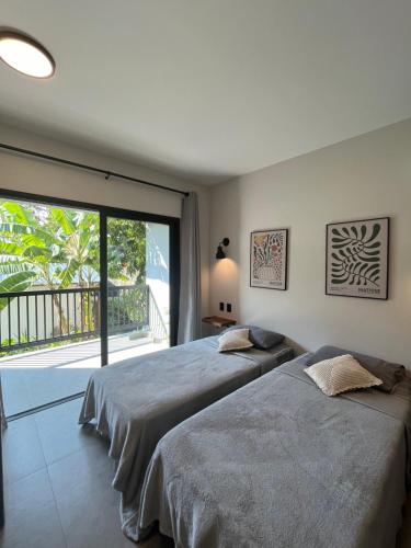 two beds in a bedroom with a large window at Pousada Villa Julião in Ilhabela
