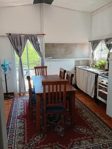 a dining room with a table and chairs and a kitchen at Refugio Amaicha in Embalse