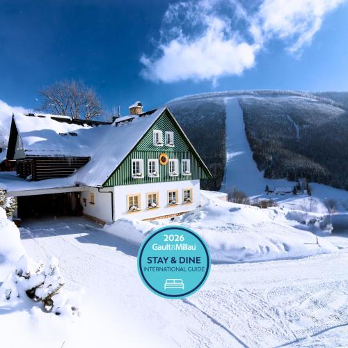 a house in the snow with a sign in front at Pension Slunečnice & Panorama Restaurant Farma in Špindlerův Mlýn