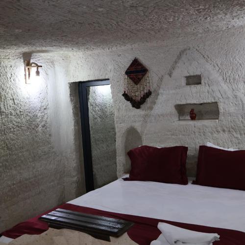 a bedroom with a white bed with red pillows at Seven Rock Cave Hotel in Göreme