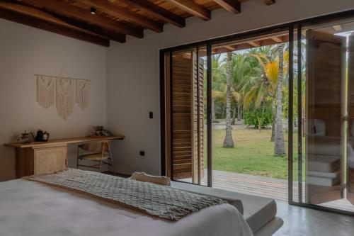 a bedroom with a bed and a sliding glass door at ICACO refugio de playa in Guachaca