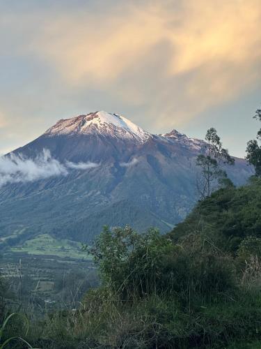 a snow covered mountain on top of a hill at Casa de campo Las Flores in Penipe