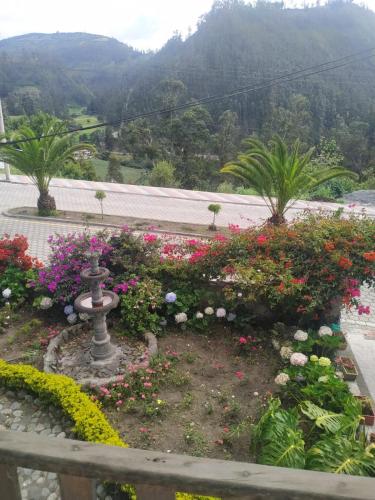 a garden with flowers and a fountain in the middle at Casa de campo Las Flores in Penipe