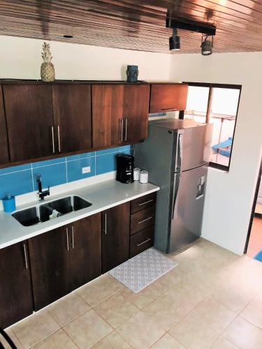 a kitchen with wooden cabinets and a stainless steel refrigerator at La buena vida ocean Tamarindo in Tamarindo