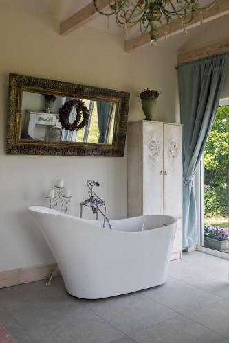 a white bath tub in a bathroom with a mirror at Zielone Zacisze in Murzynowo Kościelne
