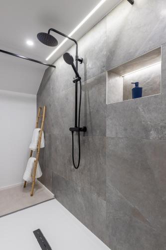 a shower with a black shower head on a wall at La Perle Bleue in Algrange