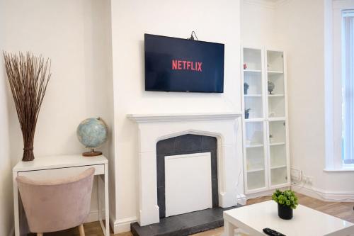 a living room with a tv above a fireplace at 4 bedrooms 8 beds Wi-FI smart tv games room in Hull