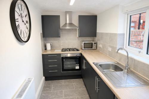 a kitchen with a sink and a clock on the wall at 4 bedrooms 8 beds Wi-FI smart tv games room in Hull