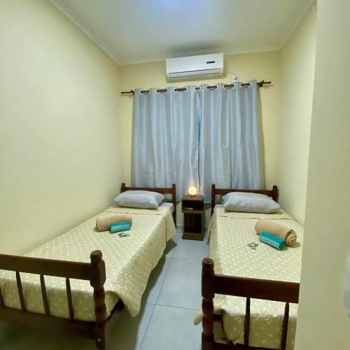 two beds in a room with a window at Casa completa com 2 quartos e garagem perto do aeroporto in Joinville