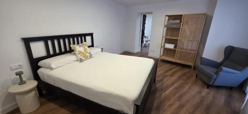 a bedroom with a bed and a blue chair at La Cueva de Villa Gardel in Icod de los Vinos