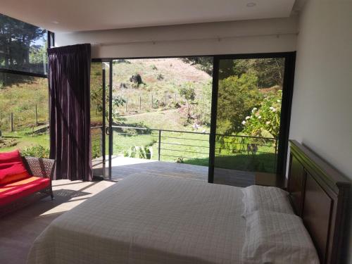 a bedroom with a bed and a large window at Casa Nébula La Cima de Dota in El Copey