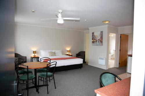 a hotel room with a bed and a table and chairs at Bella Vista Motel Hamilton in Hamilton