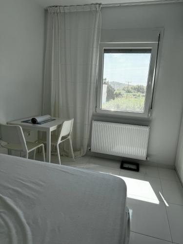 a bedroom with a bed and a table and a window at Enlightened Escape in Nea Peramos