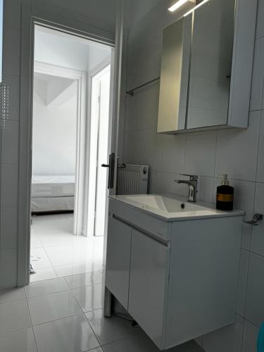 a white kitchen with a sink and a mirror at Enlightened Escape in Nea Peramos