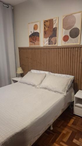 a bed in a bedroom with paintings on the wall at Apartamento Bourbon 111 in Porto Alegre