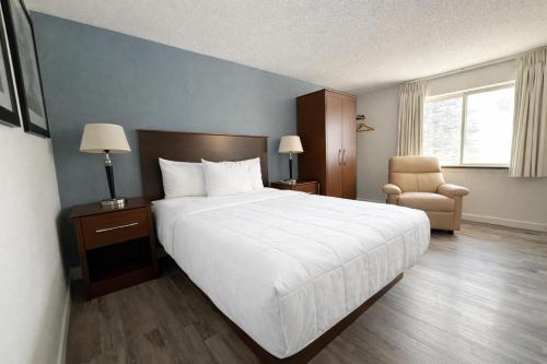 a bedroom with a large white bed and a chair at Hotel 8 in Fergus Falls