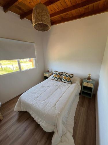 a bedroom with a large white bed with a window at Casa Lobos en Chapadmalal in La Estafeta