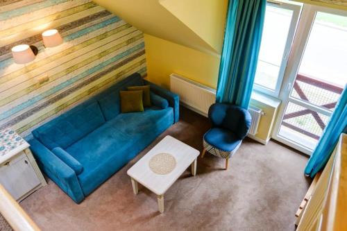 een woonkamer met een blauwe bank en een stoel bij OW Krakus I - pokoje i domki in Stegna