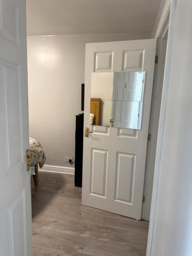 a hallway with a white door with a mirror at Bel City in Thornton Heath