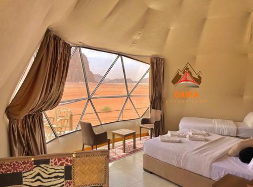 a bedroom with two beds and a large window at Daria Luxury Camp in Wadi Rum
