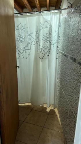 a shower with a white shower curtain in a bathroom at casa rustica dos dormitorios con pileta in Huerta Grande