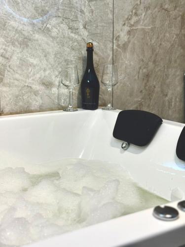 a bottle of wine and two glasses on a bath tub at Aires del Rio Apart in Villa de Soto