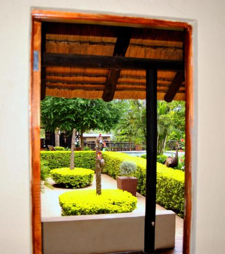 a view of a garden through a window at Palmwag Tzaneen in Tzaneen
