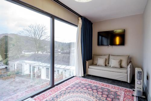 a living room with a couch and a large window at Waterhead Rooms & Suites - Parking Available Onsite in Ambleside