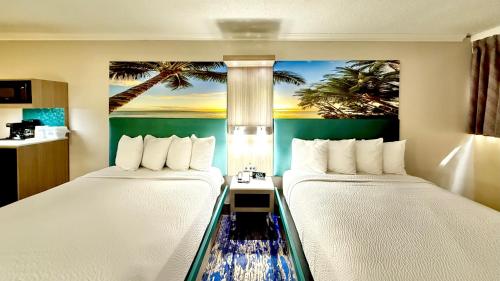 two beds in a hotel room with a palm tree mural at Days Inn by Wyndham Los Angeles LAX Airport Stadium Area in Los Angeles