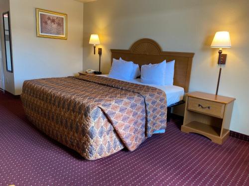 a hotel room with a large bed and a table at Sunshine inn in Centre