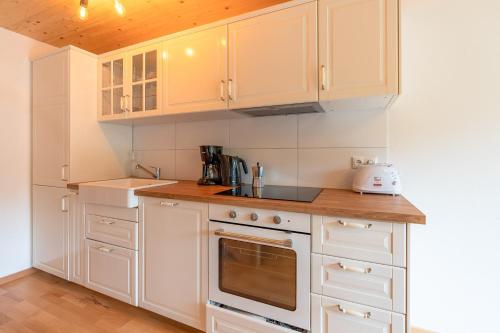a kitchen with white cabinets and a stove top oven at Sigelalp in Blaichach