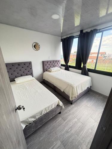 a bedroom with two beds and a window at Apartamentos campestres la Divisa in Santa Rosa de Cabal