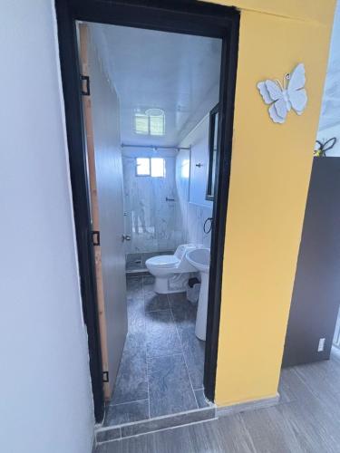 a bathroom with a toilet and a butterfly on the wall at Apartamentos campestres la Divisa in Santa Rosa de Cabal