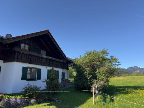 a white house in a field with a tree at Landhaus Waibel in Blaichach