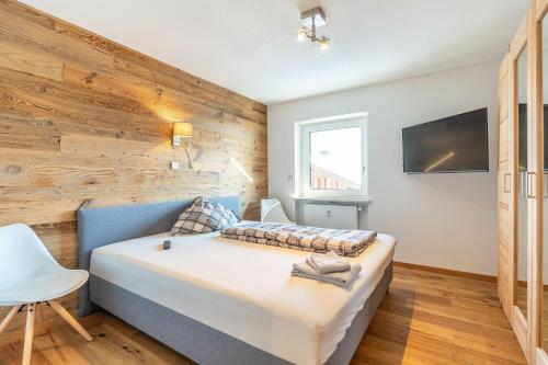 a bedroom with a bed with a wooden wall at Fewo Blick in die Berge in Ofterschwang