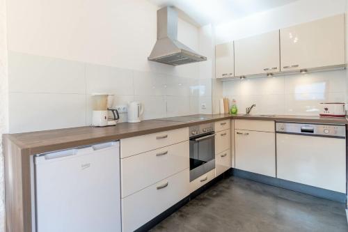 a kitchen with white cabinets and a stove top oven at Entschenkopf in Bolsterlang