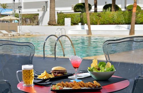 a table with a sandwich and a salad and drinks at Sol House The Studio - Calviá Beach - Adults Only in Magaluf