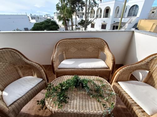 three wicker chairs and a table on a balcony at Fimar in Torre Lapillo