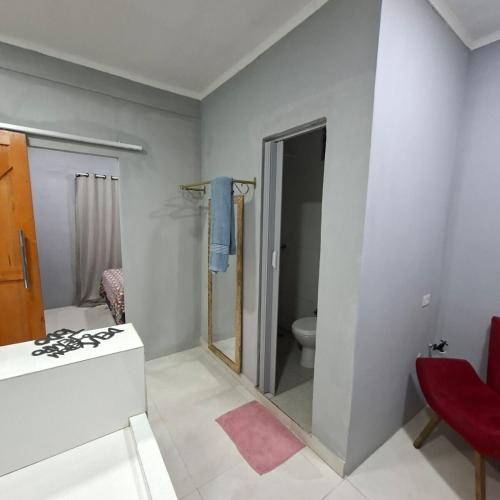 a bathroom with a toilet and a red chair at Espaço completo aconchegante no 2 andar in Belém
