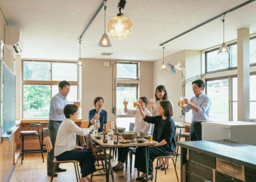 a group of people sitting at a table in a restaurant at まるもりビレッジ in Wada