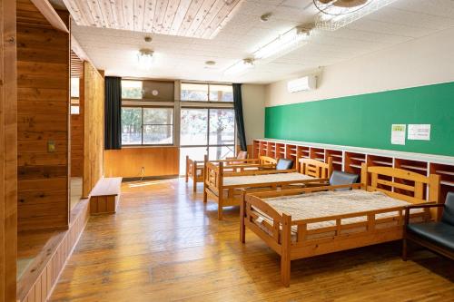 a classroom with wooden tables and benches and a green wall at まるもりビレッジ in Wada
