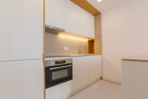 a kitchen with white cabinets and a sink and a stove at D'AUSE - New Modern Apt - 150m to Beach & Center in Esposende