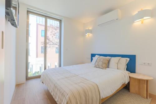 a white bedroom with a large bed and a window at D'AUSE - New Modern Apt - 150m to Beach & Center in Esposende