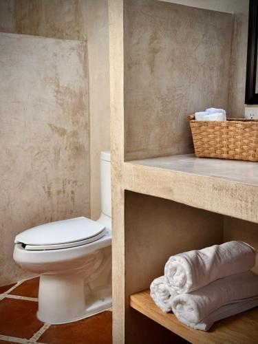 a bathroom with a toilet and a basket of towels at Casa Lavanda in San Miguel de Allende